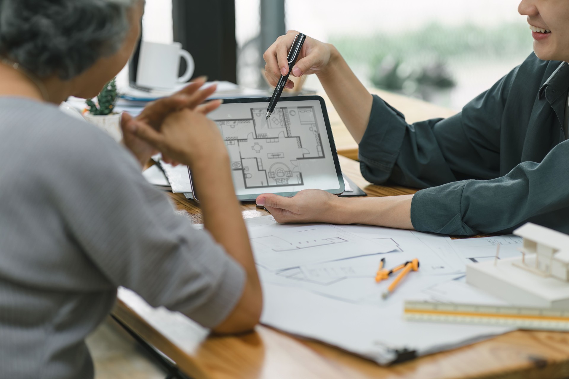 The contractor presents the house construction plans to the elderly female client.