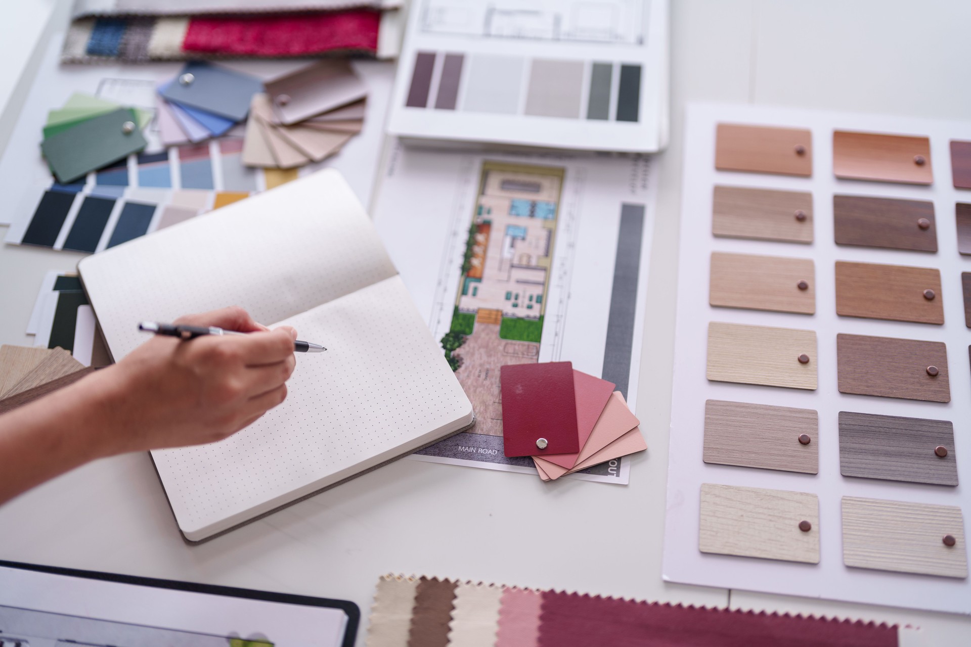 Architect plans modern home interior design project selecting materials from color palettes and fabric samples on desk