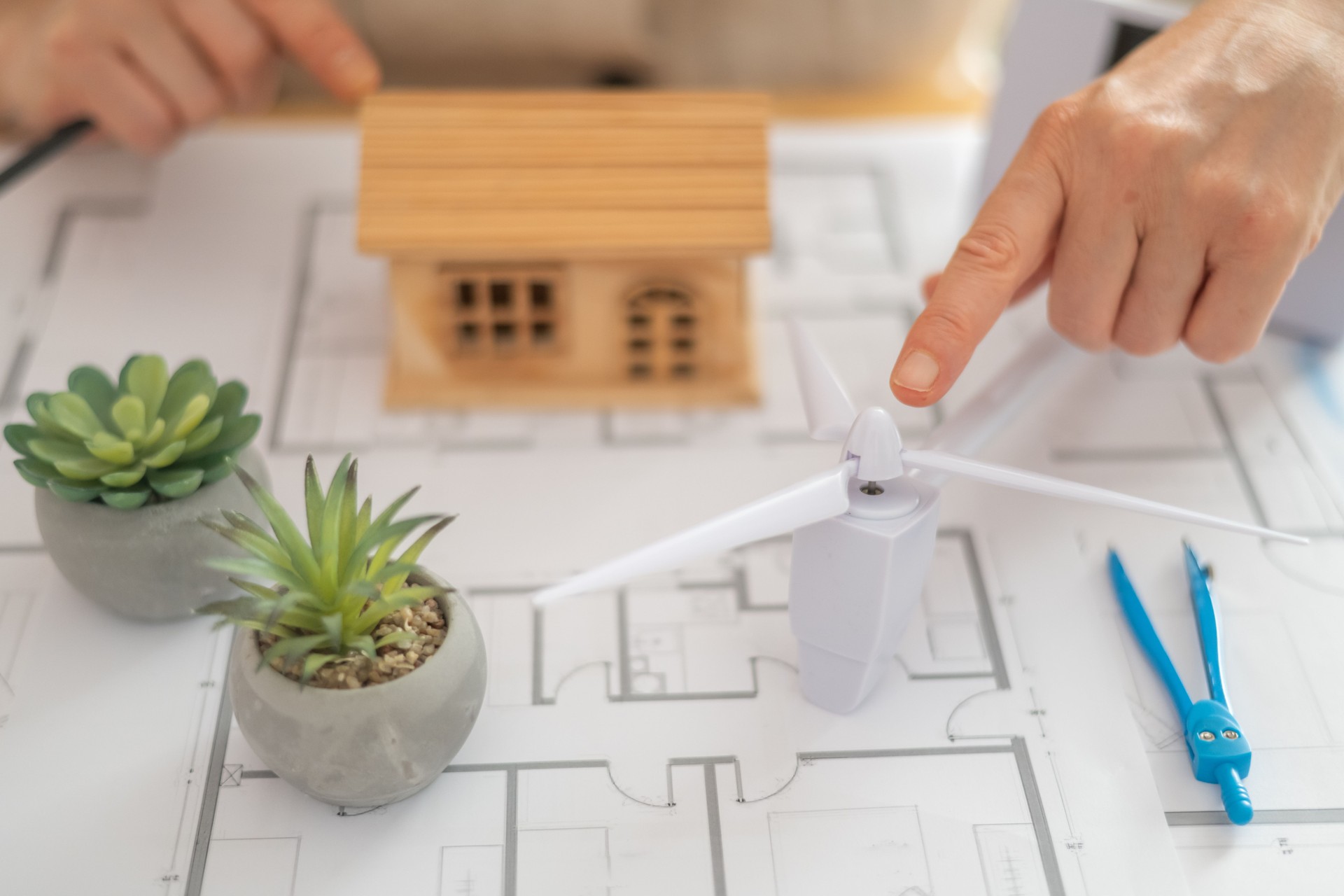 Architect designing a sustainable house powered by a wind turbine, emphasizing renewable energy and an ecological future while creating innovative solutions for green living